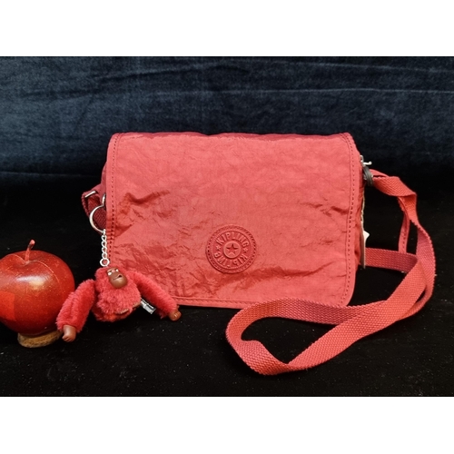 113 - A charming bright red Kipling cross body handbag with zip pouches and several additional storage spa... 