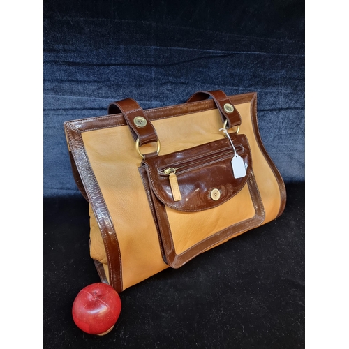 84 - A designer ladies hold-all handbag by Ted Baker. A large example in a tan material with mahogany bro... 