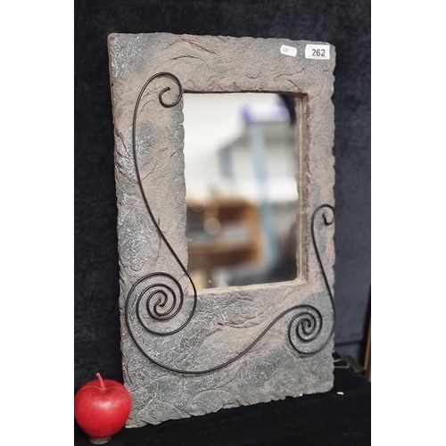 262 - A very heavy decorative wall mirror with stone effect facade and wrought metal scroll motif.