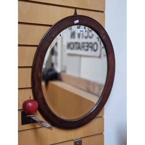 346 - A handsome example of an oval Edwardian wall mirror set in a wooden frame and with bevelled glass.