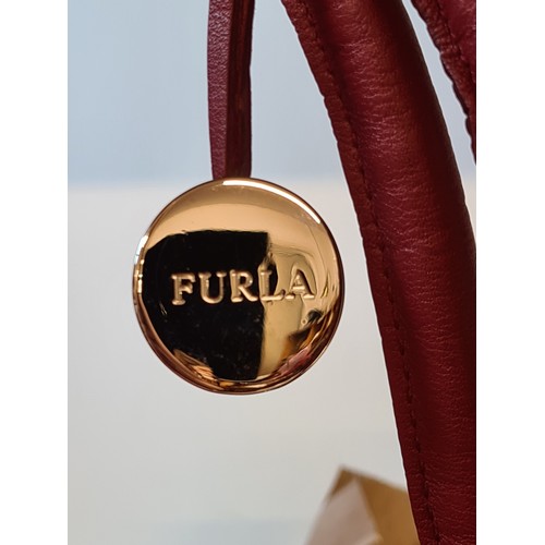 78 - A striking genuine leather ladies handbag by designer brand Furla. An elegant example in a ruby red ... 