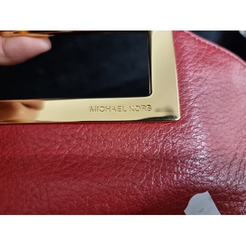 63 - Star Lot : A very stylish red leather clutch by Michael Kors featuring rectangular hardware handle, ... 