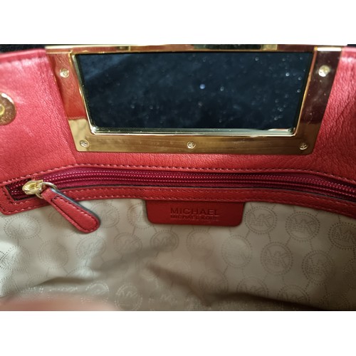 63 - Star Lot : A very stylish red leather clutch by Michael Kors featuring rectangular hardware handle, ... 