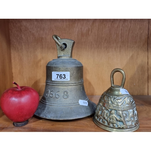 763 - Two brass bells including an example reading 1668 and a smaller ornate example with the four Evangel... 