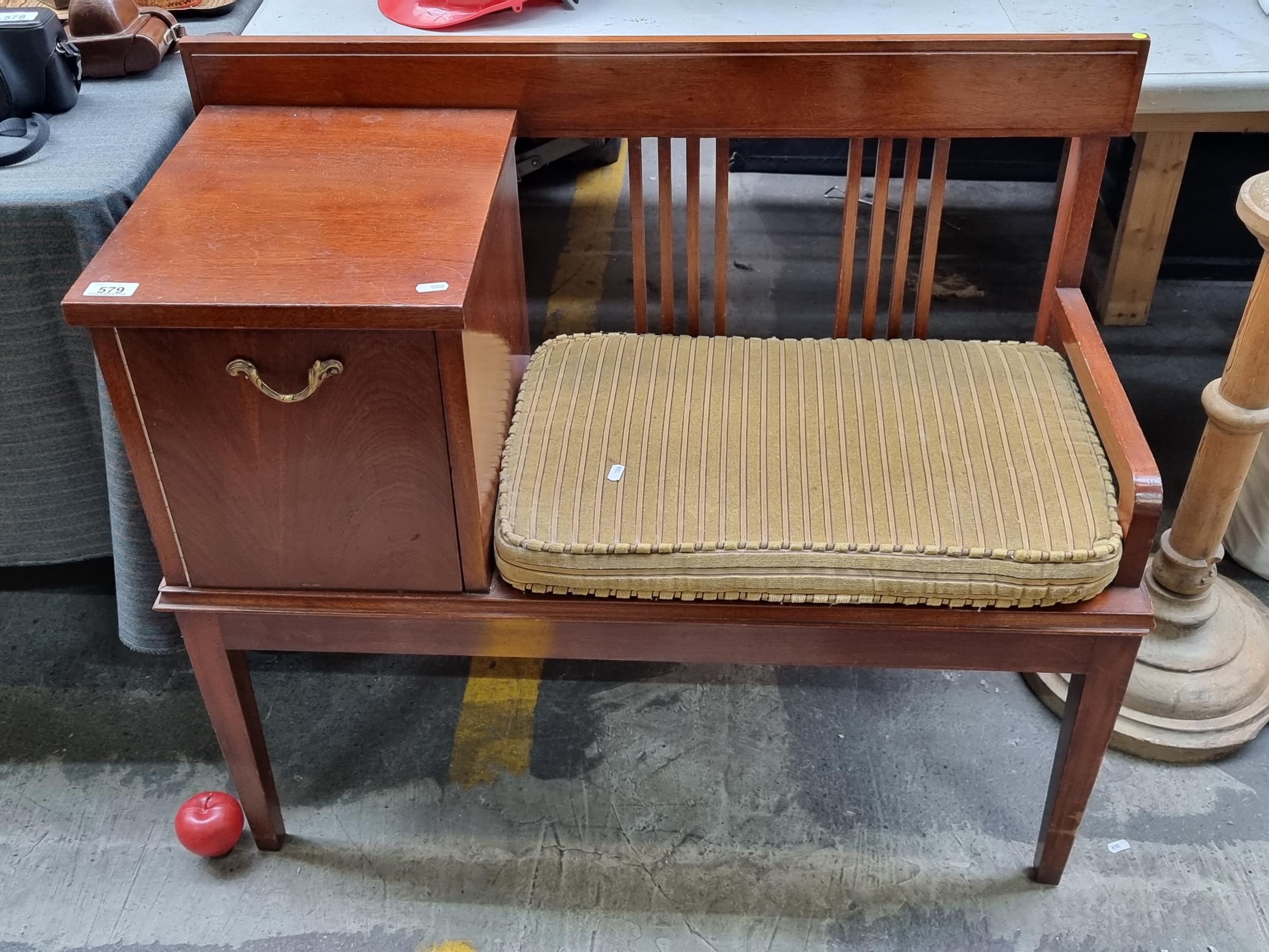 A handsome vintage 'gossip bench' telephone table with comfortable