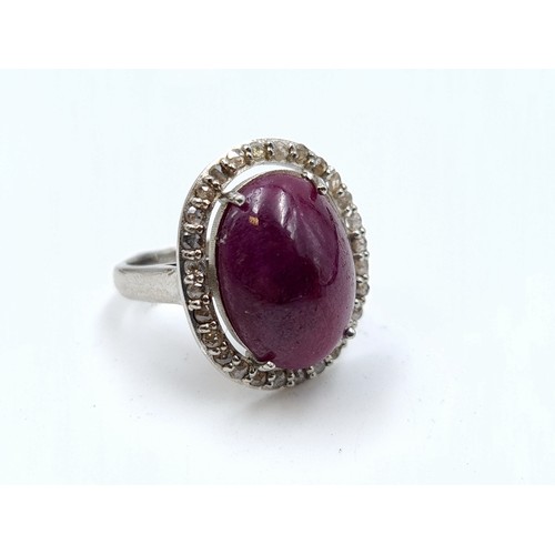 654 - Star Lot : An attractive ruby set stone ring with diamond halo setting, mounted in sterling silver. ... 