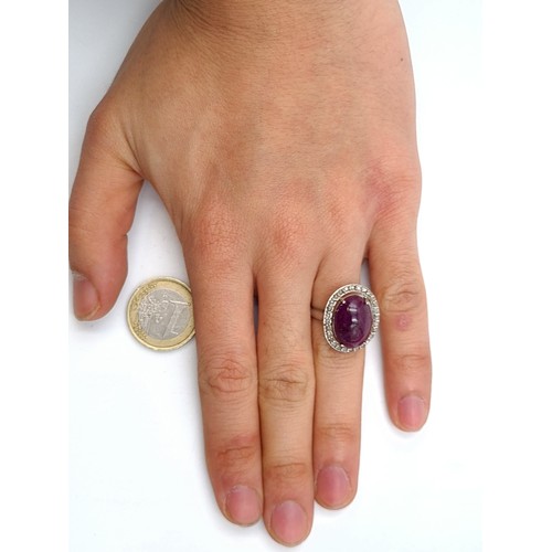 654 - Star Lot : An attractive ruby set stone ring with diamond halo setting, mounted in sterling silver. ... 