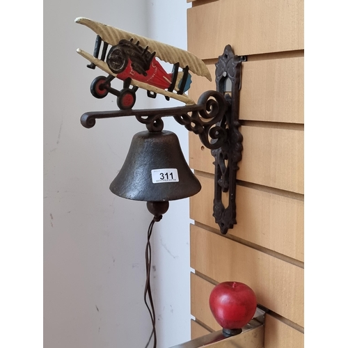 311 - A wonderful cast metal wall bell surmounted with a hand painted antique areoplane and elegant pierce... 