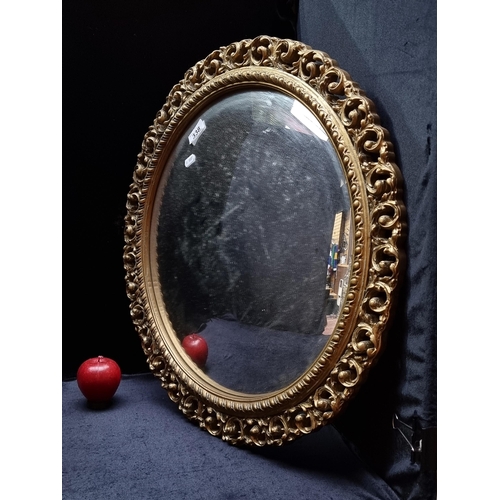 338 - A very ornate round convex wall mirror set into an intricate gilded frame with pierced scroll surrou... 