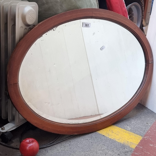 361 - A charming antique oval mirror with beveled glass and handsome string inlay to frame. H54cm x W77cm.