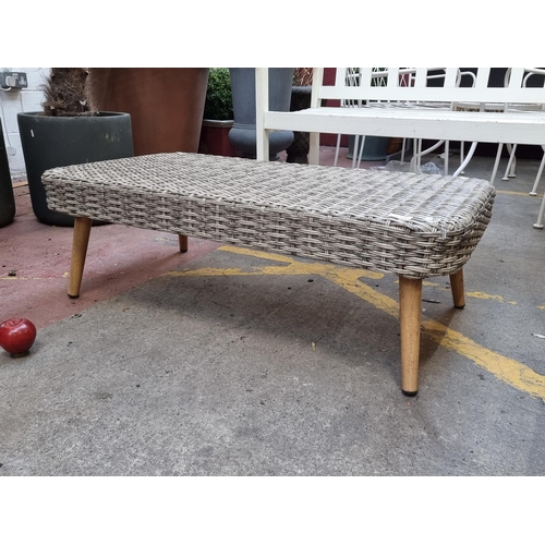 375 - A stylish outdoor patio rattan coffee table on four tapered wooden legs. L100cm x W54cm x H32cm. The... 