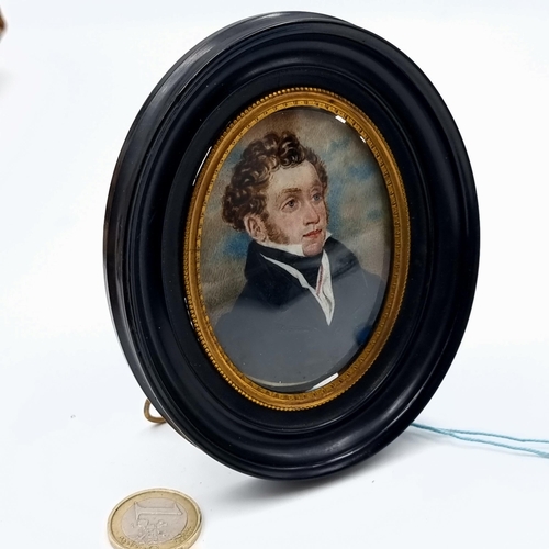 536 - A miniature portrait painting of a handsome gentleman in period dress. Housed in a oval black and gi... 