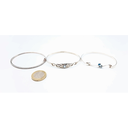 803 - Three sterling silver bangles (marked 925) including a blue gem set example with scroll setting, a l... 