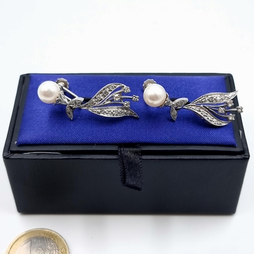 18 - A gorgeous pair of 14k white gold Diamond and Pearl drop earrings, set with an intricate setting and... 