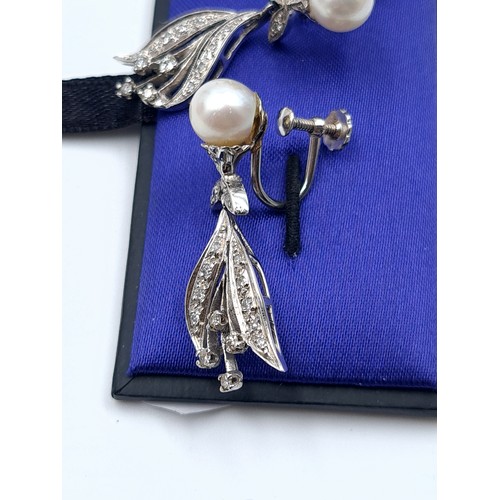 18 - A gorgeous pair of 14k white gold Diamond and Pearl drop earrings, set with an intricate setting and... 