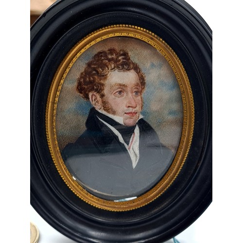 536 - A miniature portrait painting of a handsome gentleman in period dress. Housed in a oval black and gi... 