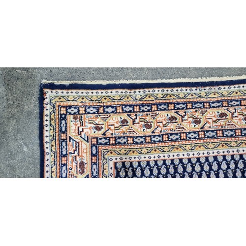 342 - A handwoven Anatolian Turkish rug in shades of blue and orange with a geometric border and central l... 