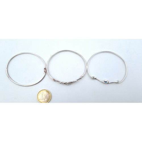 803 - Three sterling silver bangles (marked 925) including a blue gem set example with scroll setting, a l... 