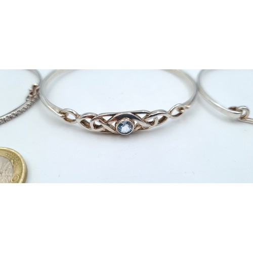 803 - Three sterling silver bangles (marked 925) including a blue gem set example with scroll setting, a l... 