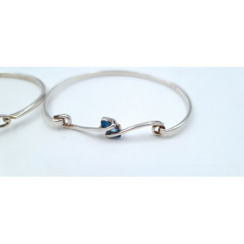 803 - Three sterling silver bangles (marked 925) including a blue gem set example with scroll setting, a l... 