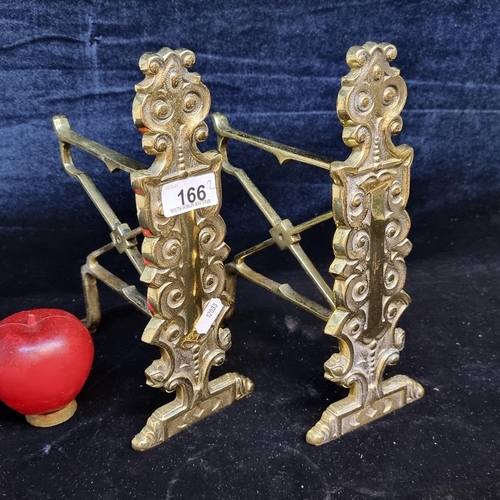 166 - A pair of elegant victorian brass fire dogs featuring lovely foliate detail and an X-shaped frame. U... 