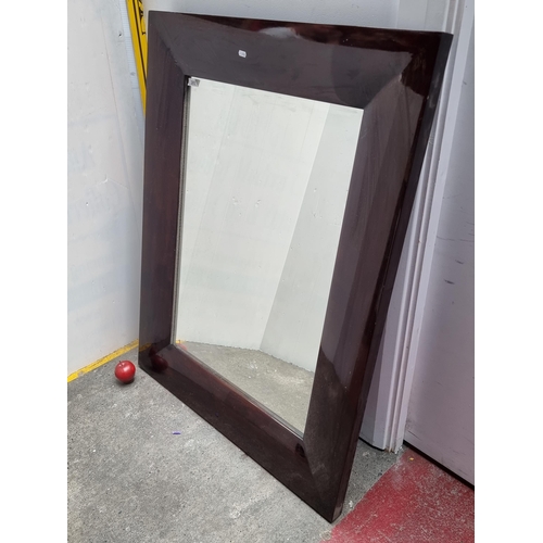 305 - A very large and heavy wall mirror held in a wooden frame with a high gloss finish.  
MM: 90 x 117 c... 