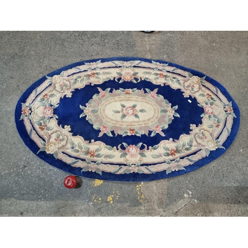 493 - A pretty Chinese wool oval rug featuring a floral design in shades of deep blue, pastel pink, green ... 