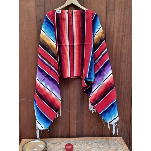 561 - A very vibrant poncho with a neck hole to centre and white fringe trim, from brand Mexitraders. In v... 