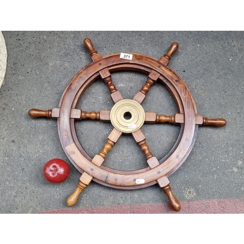 371 - A carved wooden ships steering wheel with brass centre.