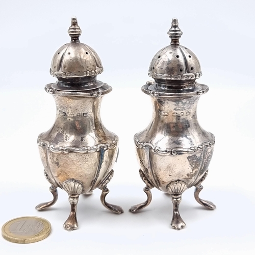 27 - An unusual pair of sterling silver cruets, set with bulbous bodies and each mounted on four shelled ... 