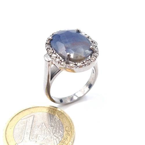8 - Star Lot : A striking example of an unusual shade of  Blue Sapphire and Diamond ring, set with a cen... 