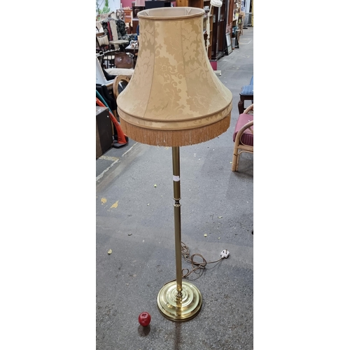 974 - A floor standing lamp with a reeded column stem and bevelled circular base. Topped with a gold damas... 