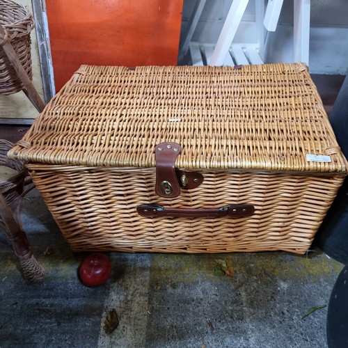 932 - A wicker basket with leather straps and handle.