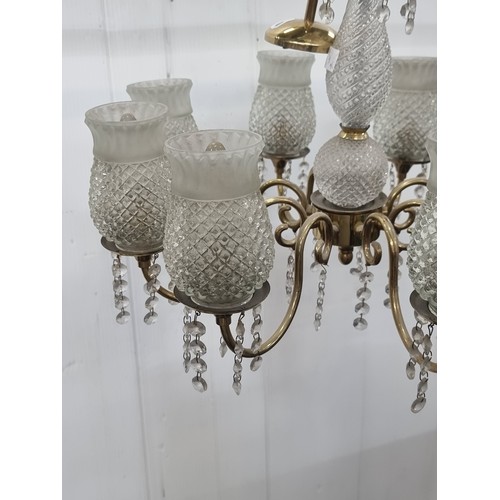 990 - An eight branch chandelier with scroll motif brass toned branches ending in delicate cut glass shade... 