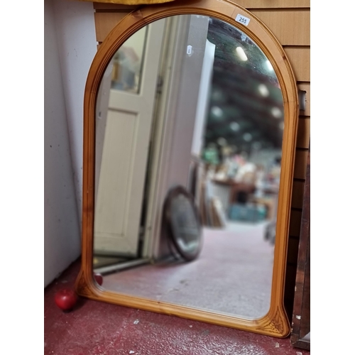 255 - A tall wooden mantle mirror with arched frame. H102cm x L68cm