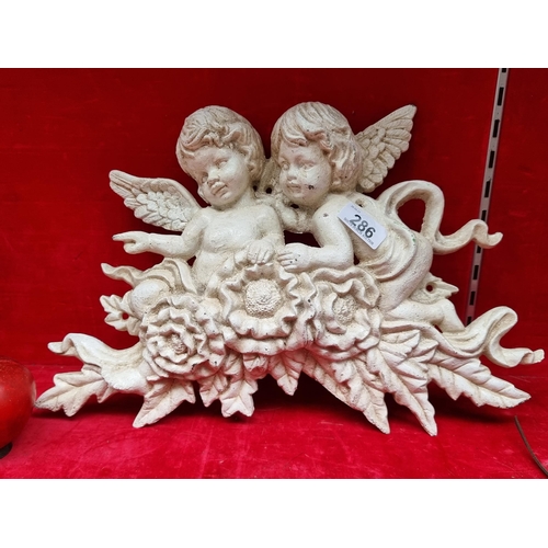 286 - A very heavy cast metal wall plaque depicting two cherubs and a bouquet of roses. In a cream finish.