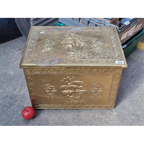 364 - An ornate brass fireside coal box, depicting three ships at sea with foliate boarder.