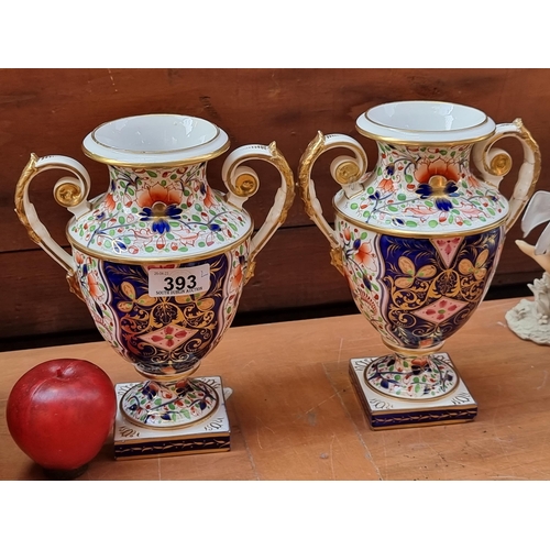 393 - A pair of beautiful porcelain pedestal urns with large spiral handles and hand painted Imari pattern... 