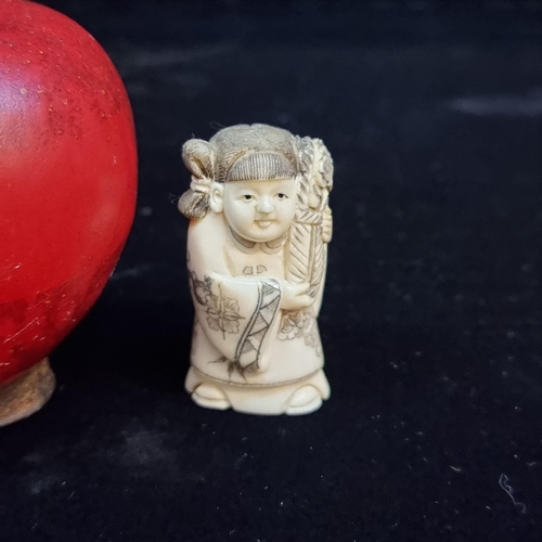 711 - A carved vintage netsuke of a young girl holding a large bunch of flowers. She is depicted with fine... 