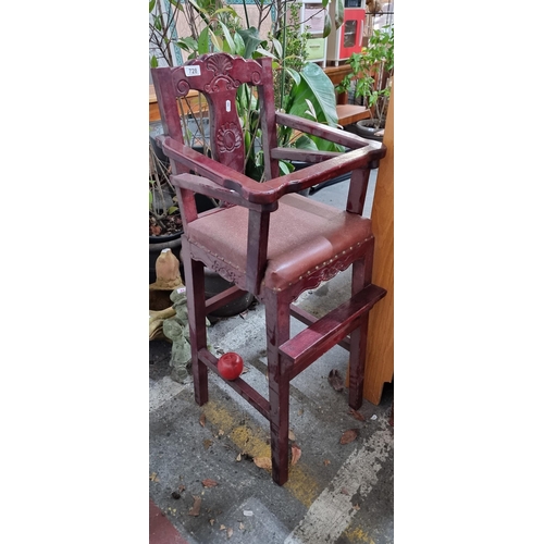 728 - A good quality wooden high chair with a carved decoration to back, hinged protective arm, padded sea... 