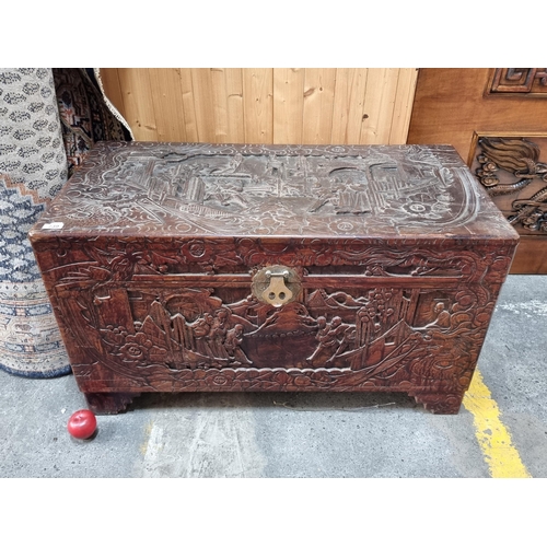 739 - A large and heavy solid wood Chinese camphor chest with hand carved landscape and figurative scenes ... 