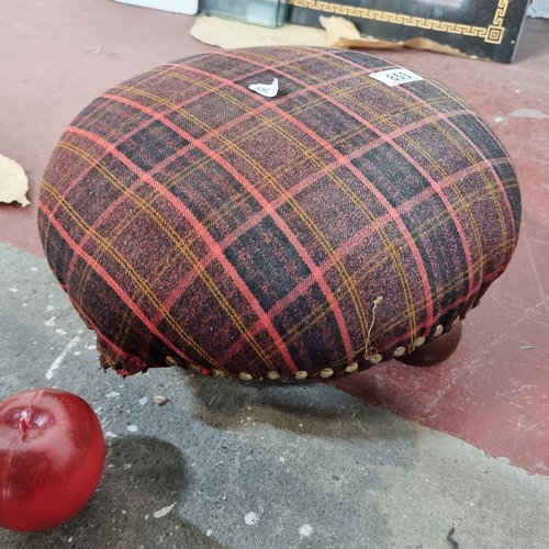 853 - A charming low footstool held on bun feet. Upholstered in a pink, navy and yellow tartan fabric with... 