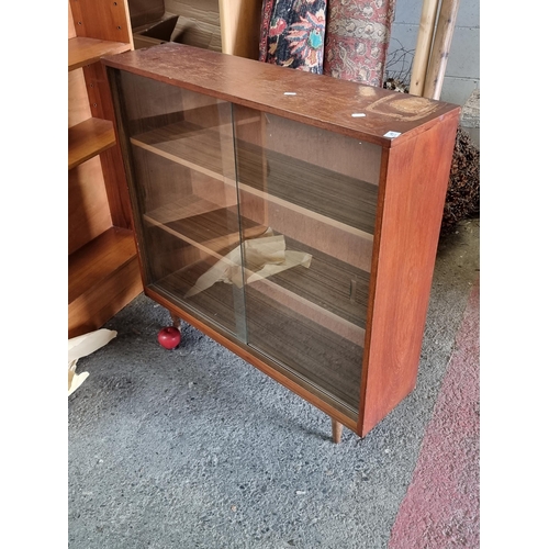 923 - A vintage Mid Century display cabinet with two shelves to interior and two glass sliding doors made ... 