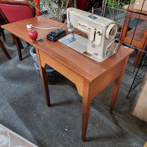 929 - A vintage Singer sewing centre including a sewing machine set into a wooden table with an extendable... 