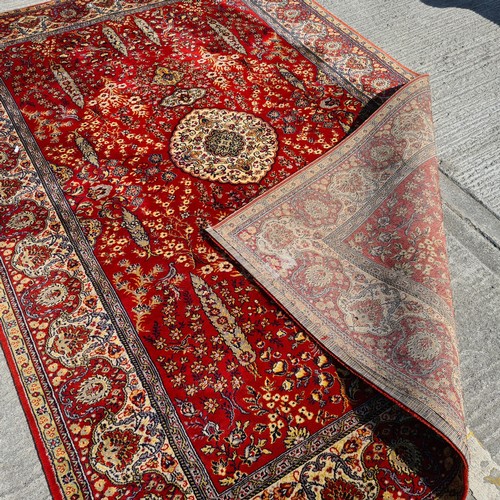 913 - A large vintage Indian floor rug. Designed in shades of red and gold with tree and floral motifs. L2... 