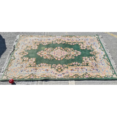 914 - A large elegant thick pile woolen rug with rich foliate vignette and border on a green background, w... 