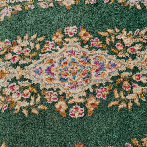 914 - A large elegant thick pile woolen rug with rich foliate vignette and border on a green background, w... 