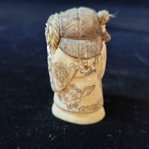 711 - A carved vintage netsuke of a young girl holding a large bunch of flowers. She is depicted with fine... 