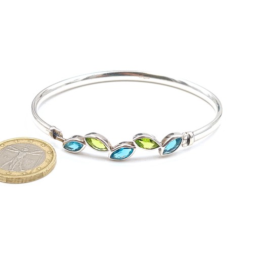 521 - A very pretty contemporary style sterling silver bangle, set with Aquamarine and Peridot stones. Enc... 