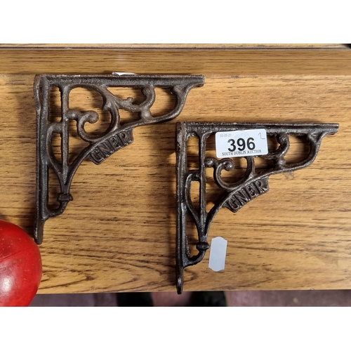 396 - A pair of cast metal wall brackets reading 'Gner' and featuring a curvilinear design.